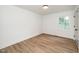 Minimalist bedroom with wood-look flooring, light walls, white trim, door, and a sun-filled window view at 1308 Broken Branch Ct, Raleigh, NC 27610