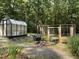 The property includes a greenhouse, storage and compost system in a verdant garden setting at 139 Trillium Pl, Chapel Hill, NC 27517
