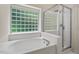 Close-up of a bathtub and shower with glass block window letting in plenty of natural light at 1406 Pebble Creek Xing, Durham, NC 27713
