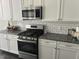 Close up of kitchen featuring stainless steel oven and microwave, granite countertops, and white cabinets at 146 Verona Villa Dr, Burlington, NC 27215