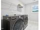 Modern laundry room with front loading washer and dryer, white tile floors, and wire shelving for storage at 195 Solomon Dr, Cameron, NC 28326