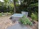 Backyard featuring a hot tub, stone patio, and lush greenery, creating an outdoor oasis for relaxation at 202 Howland Ave, Cary, NC 27513