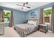 Cozy bedroom featuring carpeted floors, neutral blue walls, two windows, a ceiling fan, and stylish decor at 202 Howland Ave, Cary, NC 27513