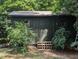 Garden shed featuring double doors, plants, and lush greenery, adding charm and practicality to the landscape at 202 Howland Ave, Cary, NC 27513