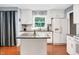 Bright kitchen featuring an island, granite countertops, white cabinets and appliances, and hardwood floors at 202 Howland Ave, Cary, NC 27513