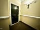 A hallway featuring a dark wooden door, light sconce, and dark colored carpet at 211 Providence Glen, Chapel Hill, NC 27514