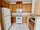 Well-lit kitchen with wooden cabinetry, white appliances, and a neutral color scheme at 211 Providence Glen, Chapel Hill, NC 27514