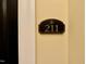 Close up of the sign outside unit 211, mounted on a neutral colored wall at 211 Providence Glen, Chapel Hill, NC 27514