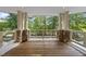Picturesque balcony with wood floors, stone columns, and scenic views of the surrounding trees at 2207 Vintage Hill Dr, Durham, NC 27712