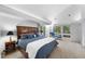 Spacious bedroom featuring a blue chaise lounge, nightstands, and backyard views at 2207 Vintage Hill Dr, Durham, NC 27712
