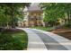 Stunning exterior view of a stone and glass home through a tree-lined entrance, complete with a curved driveway at 2207 Vintage Hill Dr, Durham, NC 27712