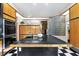 Modern kitchen featuring wood cabinets, black countertops, checkerboard floors, and stone wall accent at 2207 Vintage Hill Dr, Durham, NC 27712