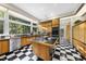 Retro kitchen with a large island, wood cabinets, black countertops, checkerboard floor, and large windows at 2207 Vintage Hill Dr, Durham, NC 27712