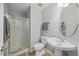 Well-lit bathroom featuring a glass shower and pedestal sink with a round mirror at 2419 Rogerson St, Raleigh, NC 27614