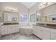 Elegant main bathroom featuring dual vanities, a soaking tub with decorative tiling, and decorative windows at 2419 Rogerson St, Raleigh, NC 27614