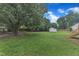 Large backyard featuring mature trees, a well-maintained lawn, shed, and wooden steps leading to a deck at 2528 Barwick Dr, Durham, NC 27704
