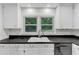 Close up of kitchen sink and white cabinets with black countertop and view of the backyard at 2528 Barwick Dr, Durham, NC 27704