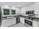 Well-lit kitchen featuring white cabinets, stainless steel appliances, and large windows for ample natural light at 2528 Barwick Dr, Durham, NC 27704