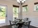 Cozy dining area with a glass table, wainscoting, and natural light from windows and a door to the exterior at 2609 Kilmartin Dr, Fuquay Varina, NC 27526