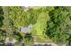 An aerial view showing a house surrounded by lush trees and a large grassy yard at 3012 Optimist Farm Rd, Apex, NC 27539
