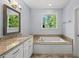 Bathroom with a soaking tub, granite countertops, and a large window with natural light at 311 Rassie Crabtree Rd, Rougemont, NC 27572