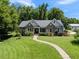Charming stone-accented home with lush lawn and landscaped walkway, surrounded by mature trees at 311 Rassie Crabtree Rd, Rougemont, NC 27572