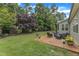 Lush backyard featuring a brick patio with outdoor seating, manicured lawn, and mature trees at 3111 Virginia Pine Ln, Apex, NC 27539