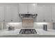 Modern kitchen featuring stainless steel gas cooktop, mosaic backsplash and white cabinets at 3111 Virginia Pine Ln, Apex, NC 27539