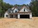 New two-story home under construction featuring an attached two-car garage and a covered porch in wooded area at 393 Abingdon Farms Dr, Selma, NC 27576