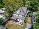 Aerial view of a two-story home with a screened porch, patio with a firepit, and a fenced-in yard surrounded by mature trees at 425 Morrison Ave, Raleigh, NC 27608