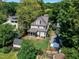 Aerial view of a two-story home featuring a screened porch, a fenced-in backyard, patio and firepit amongst lush, mature trees at 425 Morrison Ave, Raleigh, NC 27608