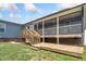 A screened back porch with wooden deck, steps, and a hot tub on the grass with blue siding on the house at 45 Imperial Dr, Clayton, NC 27527
