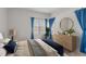 Bright bedroom with a large window, blue accents, and a stylish dresser with a round mirror at 6131 Summerpointe Pl # 101, Raleigh, NC 27606