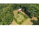 An aerial view reveals a red barn next to a fenced in garden, surrounded by a verdant forest at 7849 Circle L Trl, Rougemont, NC 27572