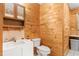 Cozy half-bath features wood-paneled walls, sink, toilet, and window, offering a rustic charm at 7849 Circle L Trl, Rougemont, NC 27572