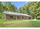 Beautiful stone home with a metal roof, lush lawn, and covered porch showcasing a serene and inviting country setting at 7849 Circle L Trl, Rougemont, NC 27572