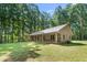 Stone home featuring a metal roof and inviting covered porch, set in a serene environment with mature trees and lawn at 7849 Circle L Trl, Rougemont, NC 27572