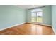 Bedroom featuring hardwood floors and a large arched window overlooking property at 8415 Meadow View Ln, Bahama, NC 27503
