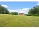 Large grassy yard featuring a stately brick home surrounded by trees at 8415 Meadow View Ln, Bahama, NC 27503