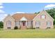 Charming brick home with red accents, landscaped lawn and inviting covered front entry at 8415 Meadow View Ln, Bahama, NC 27503