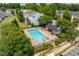 Community swimming pool surrounded by greenery, fencing, and building with shaded seating at 8620 Neuse Club Ln # 107, Raleigh, NC 27616