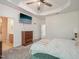 Bright bedroom featuring tray ceiling, ceiling fan, TV and ensuite bathroom at 903 Grace Point Rd, Morrisville, NC 27560