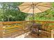 Wooden deck with a table and chairs, umbrella, and surrounded by green trees at 1100 Brooks Ave, Raleigh, NC 27607