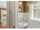 Well-lit powder room with white fixtures, patterned wallpaper, round mirror and window at 1100 Brooks Ave, Raleigh, NC 27607