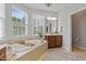 Bright bathroom features a soaking tub beneath large windows, vanity, and a neutral color palette at 113 Market Cross Ct, Holly Springs, NC 27540