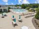 A large community pool complex featuring lounge chairs, tables with umbrellas, and a water slide area at 113 Market Cross Ct, Holly Springs, NC 27540