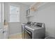 Well-lit laundry room features modern washer and dryer set, storage shelf, and large window at 113 Market Cross Ct, Holly Springs, NC 27540