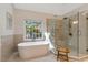 Bright bathroom showcasing a soaking tub under a window and a frameless walk-in shower at 116 Berry Hill Dr, Raleigh, NC 27615