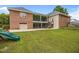 Expansive backyard featuring a brick house, a green lawn, and a green slide at 1672 Wheeler Dr, Angier, NC 27501