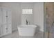 Modern bathroom features a standalone tub, neutral walls, and a glass block window for natural light at 1672 Wheeler Dr, Angier, NC 27501